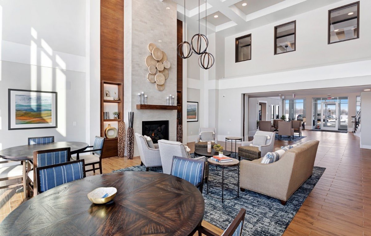 A spacious and elegantly designed living room featuring a fireplace, high ceilings, and comfortable seating.