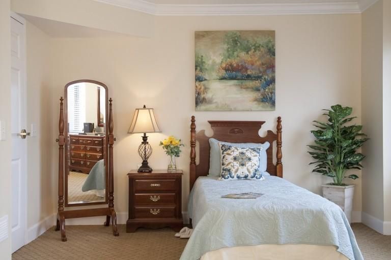 A cozy bedroom with a single bed, wooden furniture, and a decorative painting on the wall.