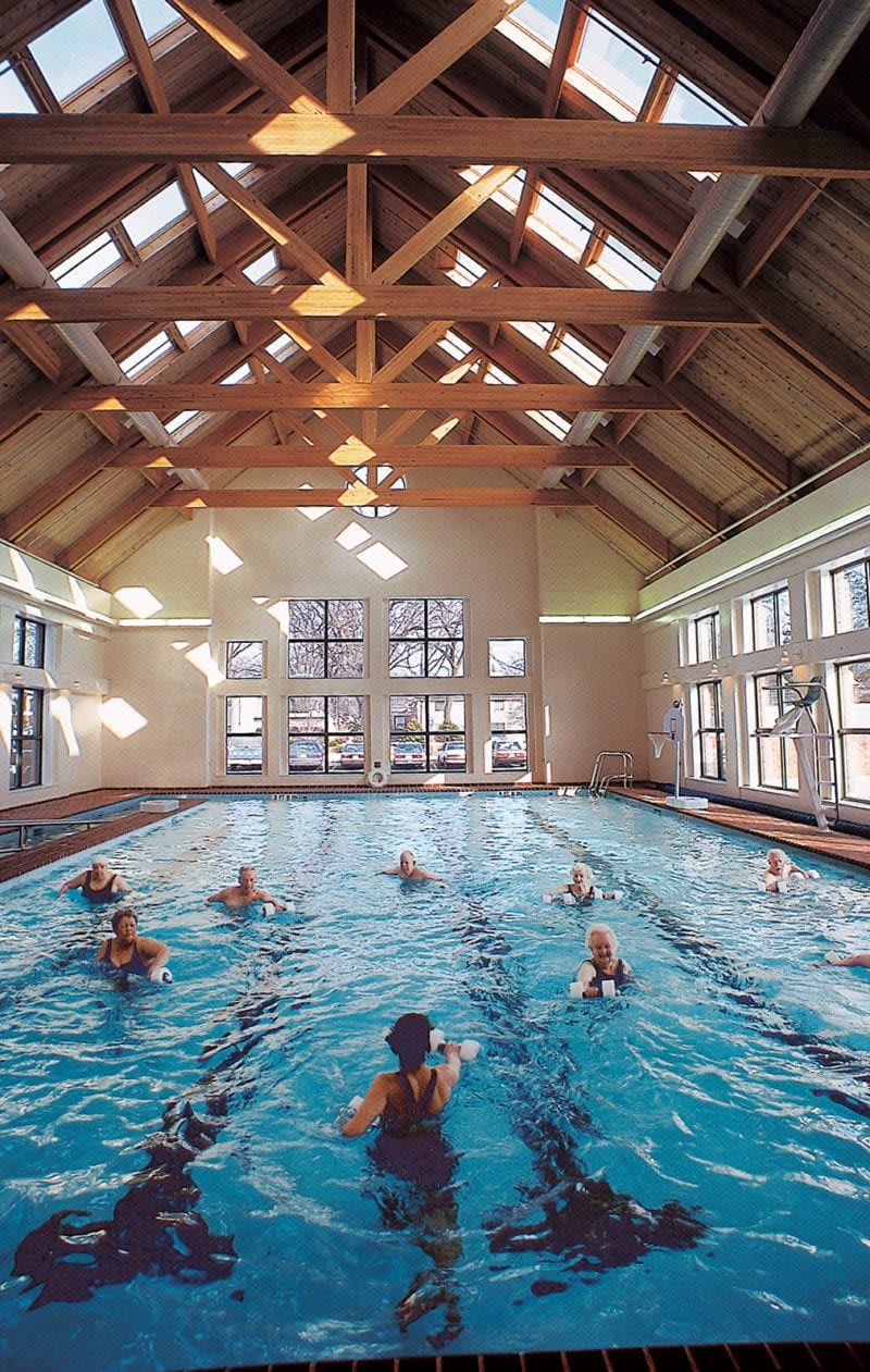 A group of people enjoying a swim session in an indoor pool with natural lighting.
