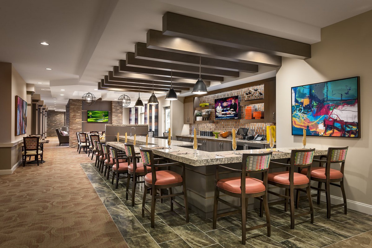 A modern restaurant interior featuring bar seating and televisions.