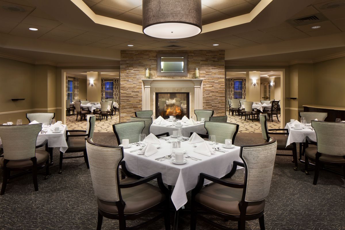 An elegant restaurant dining room with a central fireplace and beautifully set tables.