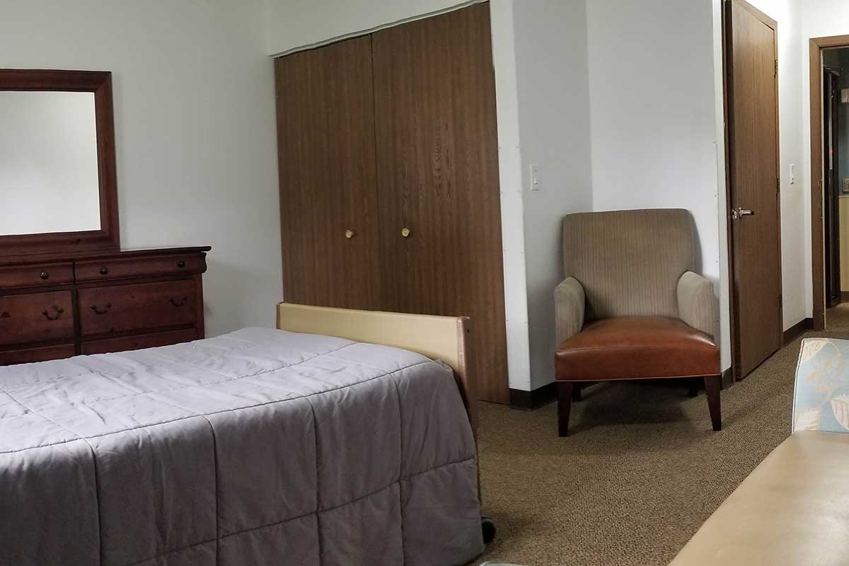 Simple bedroom with a bed, chair, and closet.
