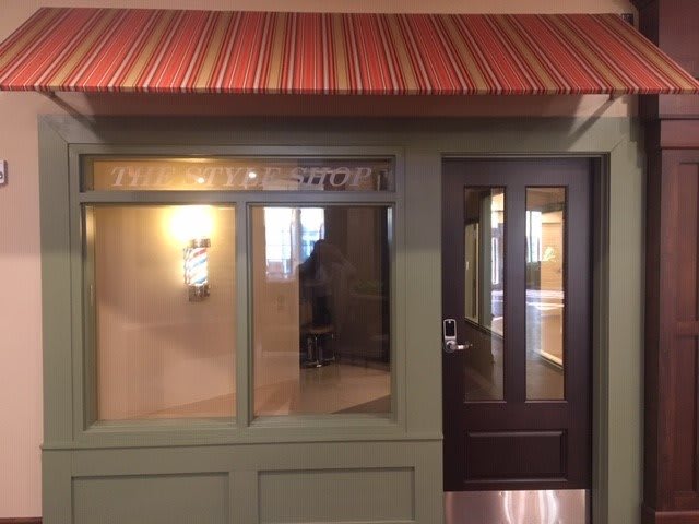 A quaint storefront with a striped awning and large windows.