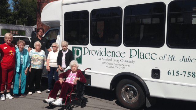 A group of elderly women posing in front of a Providence Place van.