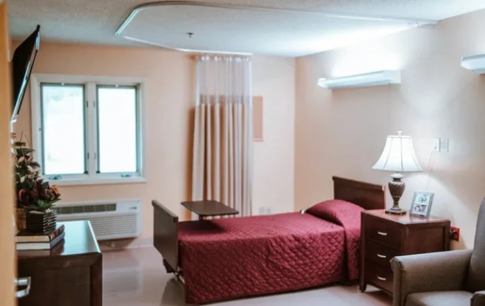 A hospital room with a single bed, wooden furniture, and a soft ambient light.