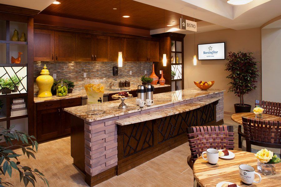 A modern kitchen with wooden cabinetry and a stylish countertop, featuring pendant lighting and decorative accents.