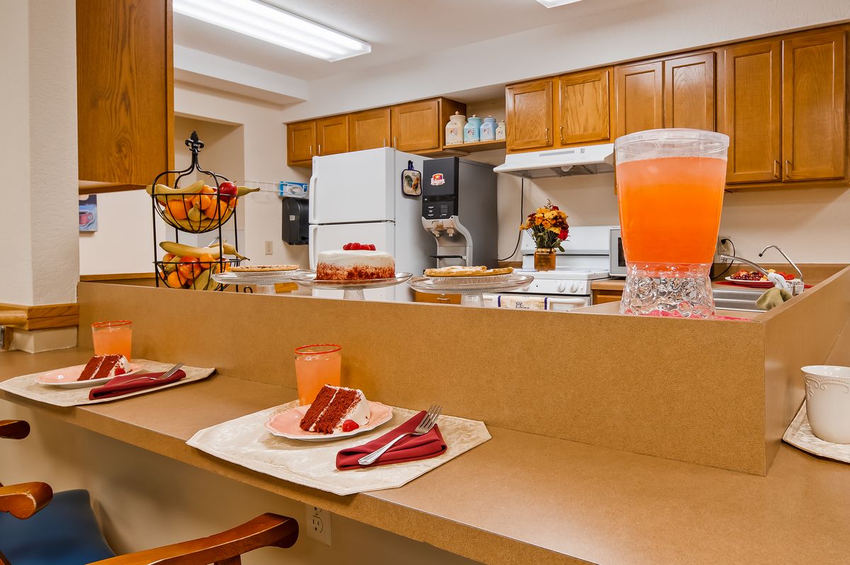 A cozy kitchen with a countertop set for dining, featuring cake slices and a pitcher of juice.