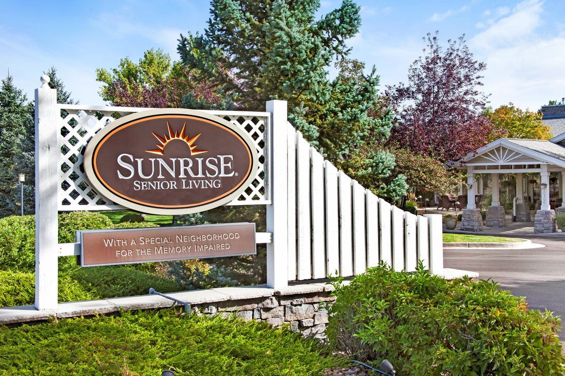 Entrance sign for Sunrise Senior Living surrounded by lush greenery.