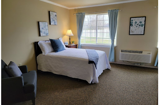 A cozy, well-lit bedroom featuring a single bed, soft furnishings, and natural light streaming in through the window.
