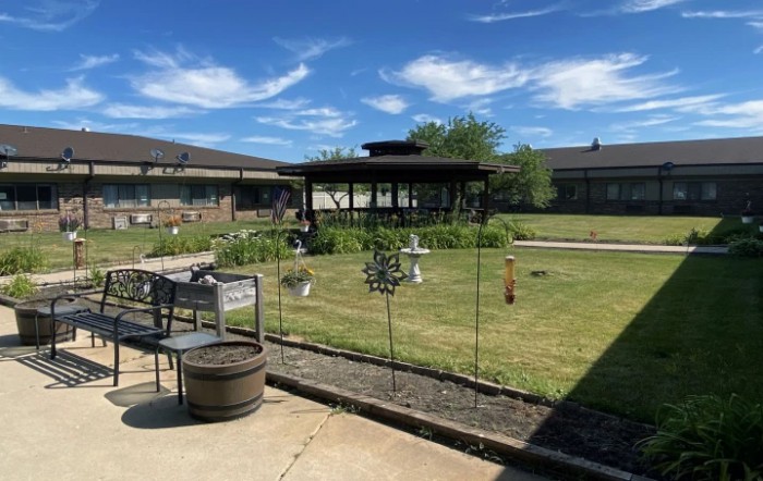 A sunny garden with a gazebo and surrounding buildings.