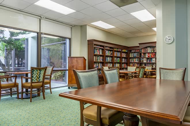 A quiet library space with bookshelves, a large table, and chairs for reading and study.