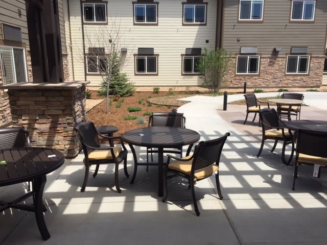 A sunny outdoor patio area with tables and chairs set up near a building.