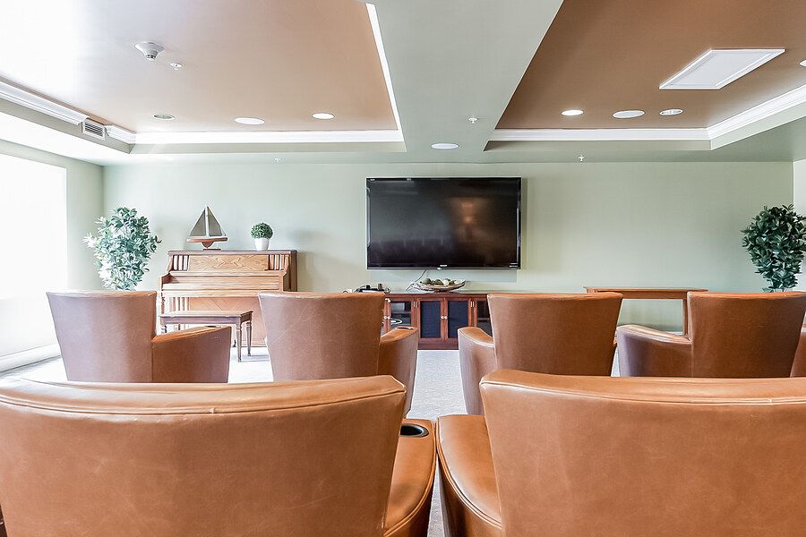 A modern lounge with comfortable seating, a television, and a piano.