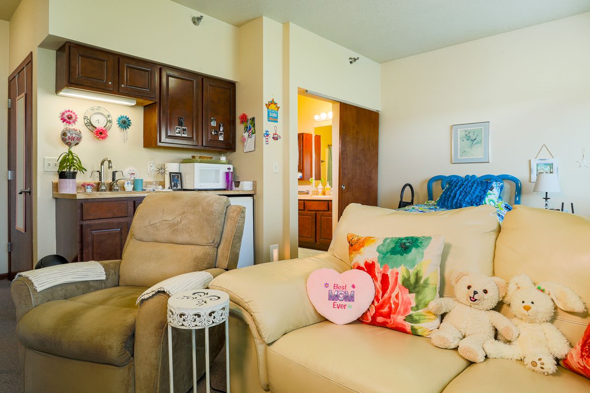 A cozy living room with a sofa, colorful pillows, and a view into the kitchen area.