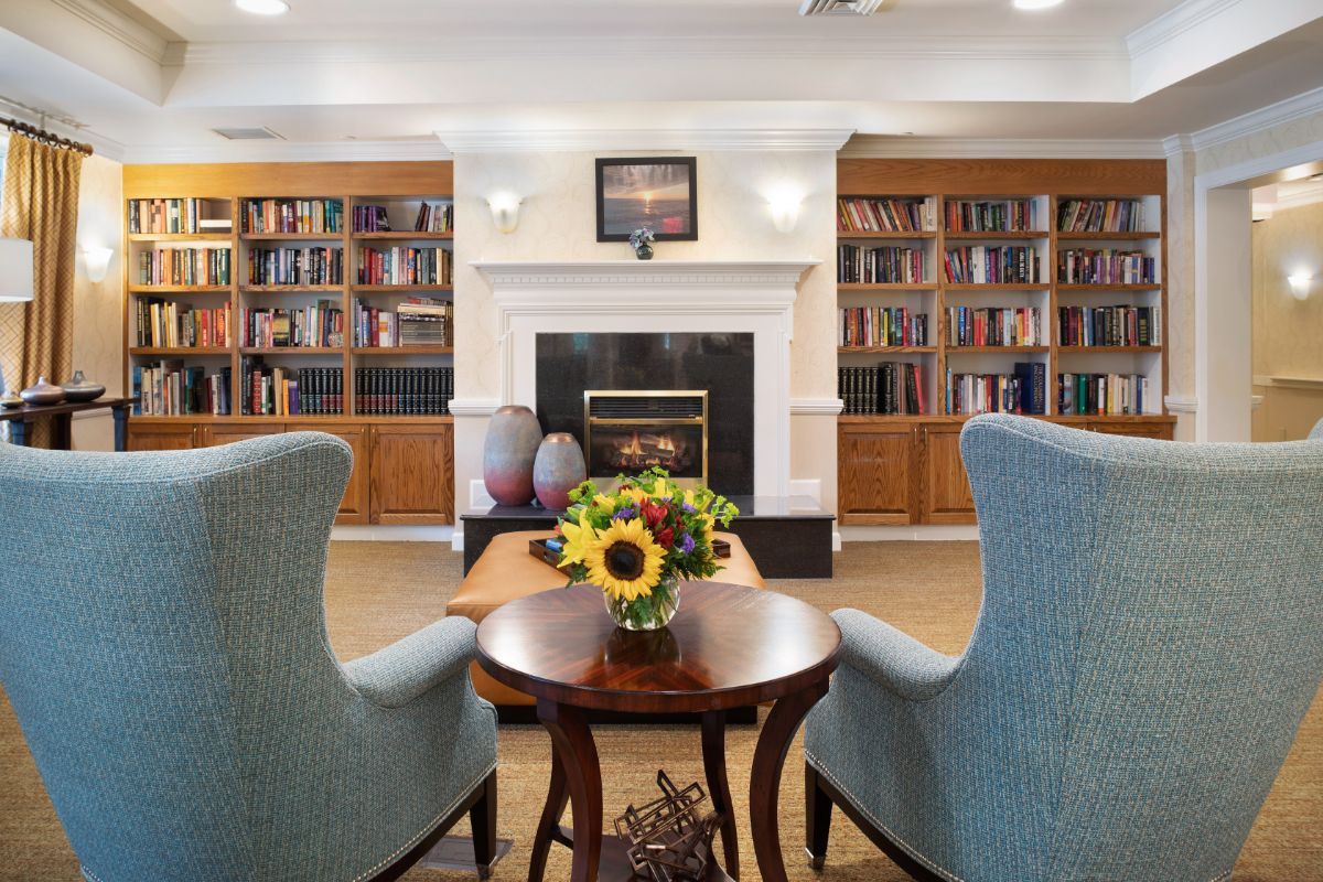Cozy library with armchairs and a fireplace surrounded by bookshelves.