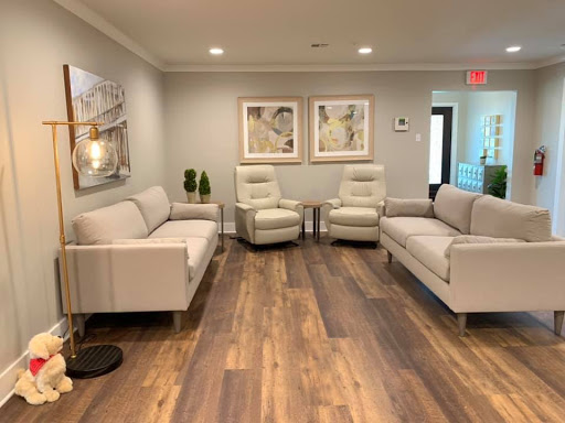 A modern waiting room featuring contemporary furniture, artwork, and warm wood flooring.