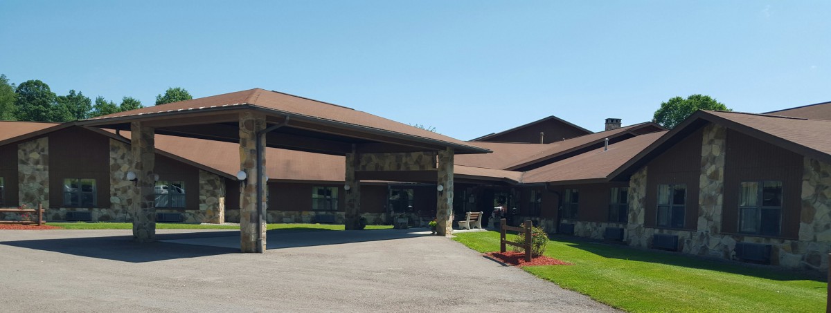 A building with a covered entrance and a driveway, surrounded by well-maintained lawns on a clear day.
