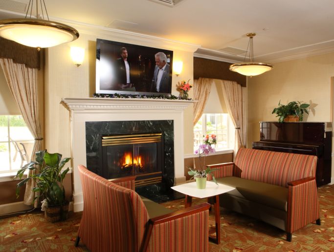 A cozy living room with a fireplace, sofas, and a television above the mantel.