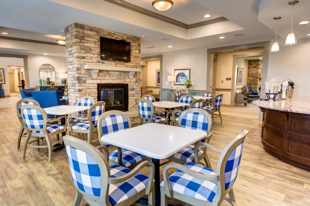 A modern dining area with checkered chairs and a fireplace.
