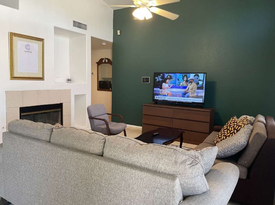 A cozy living room with a sofa facing a television on a green accent wall.