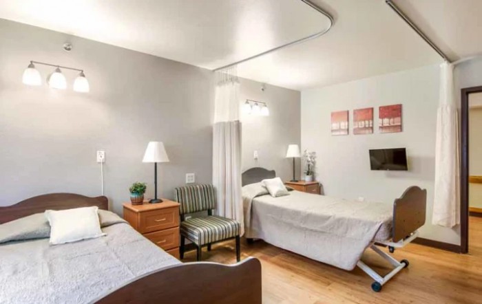 A cozy bedroom with twin beds and soft lighting, featuring a stylish armchair and decorative wall art.