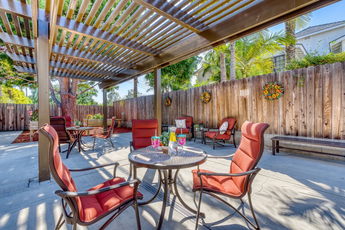 A cozy outdoor patio with red cushioned chairs under a pergola, perfect for relaxation.