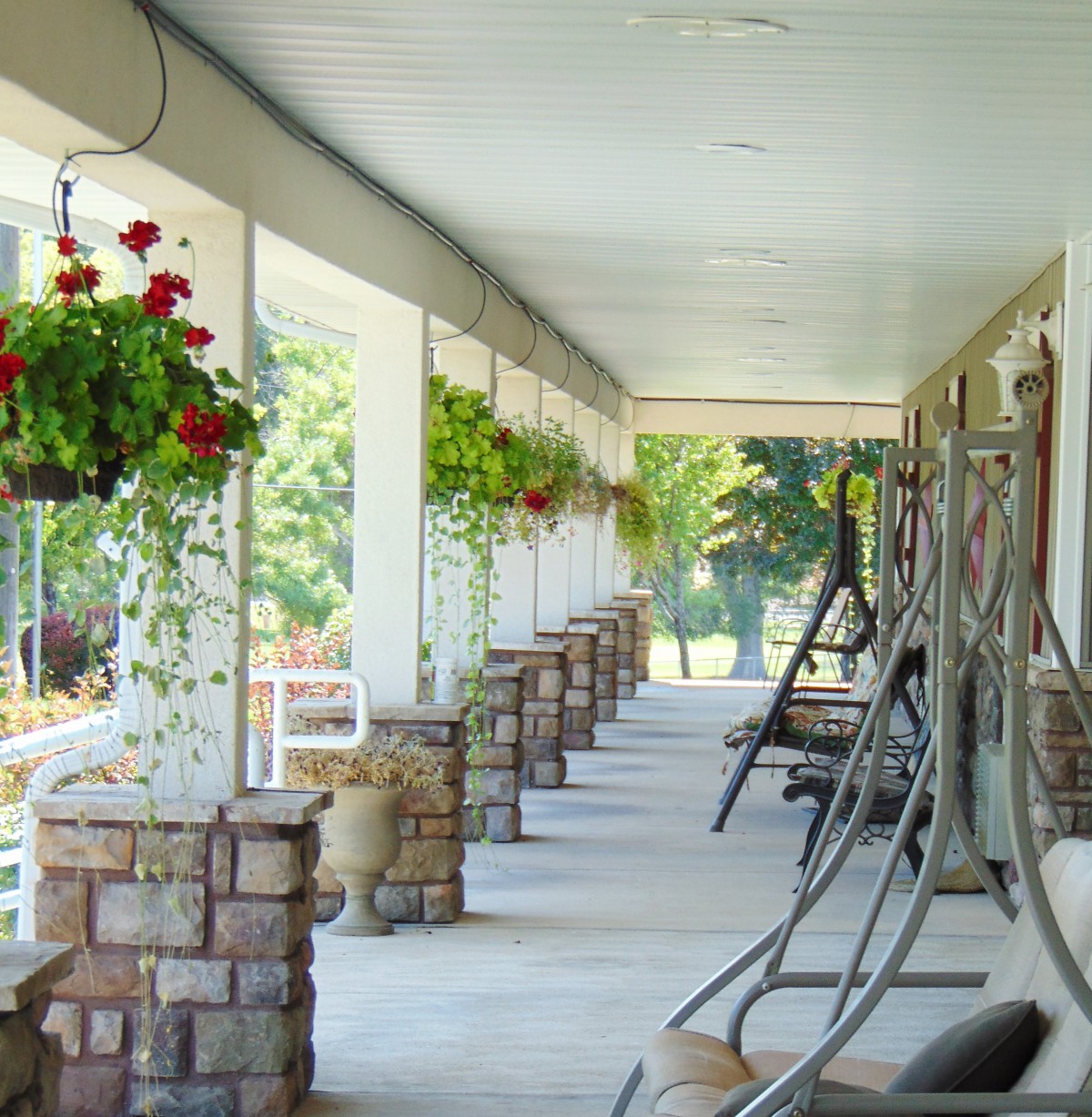 A long porch with swings and hanging flower baskets.