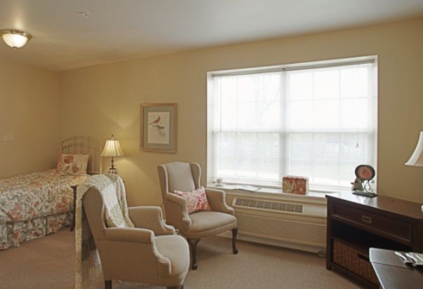A cozy living room with comfortable chairs, a lamp, and a large window.
