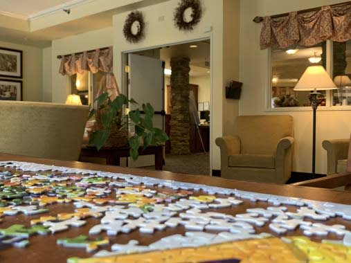 A cozy living room with a puzzle in progress on the table.