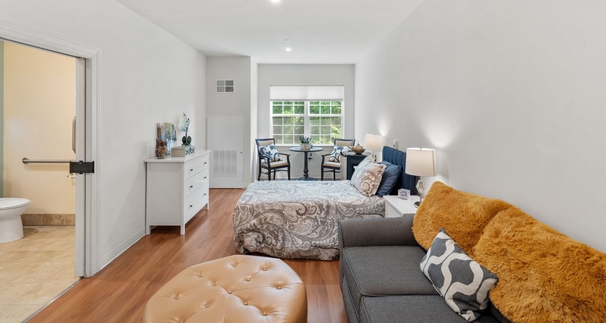 A cozy and modern studio apartment with a comfortable bed, seating area, and bright natural lighting.