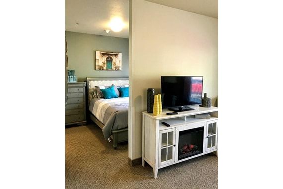A cozy room featuring a bedroom and living area with a TV on a white console.