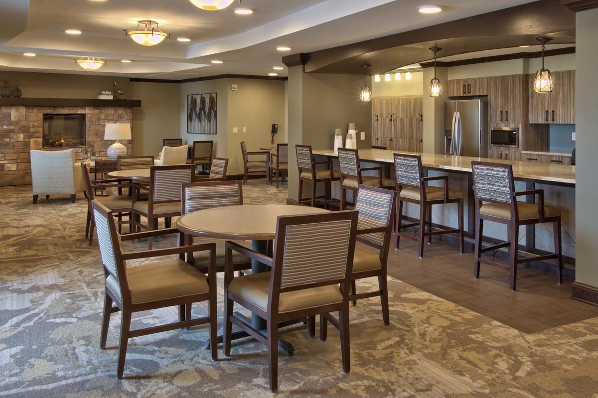 An elegantly designed dining area with tables, chairs, and a bar counter, featuring warm lighting and tasteful decor.