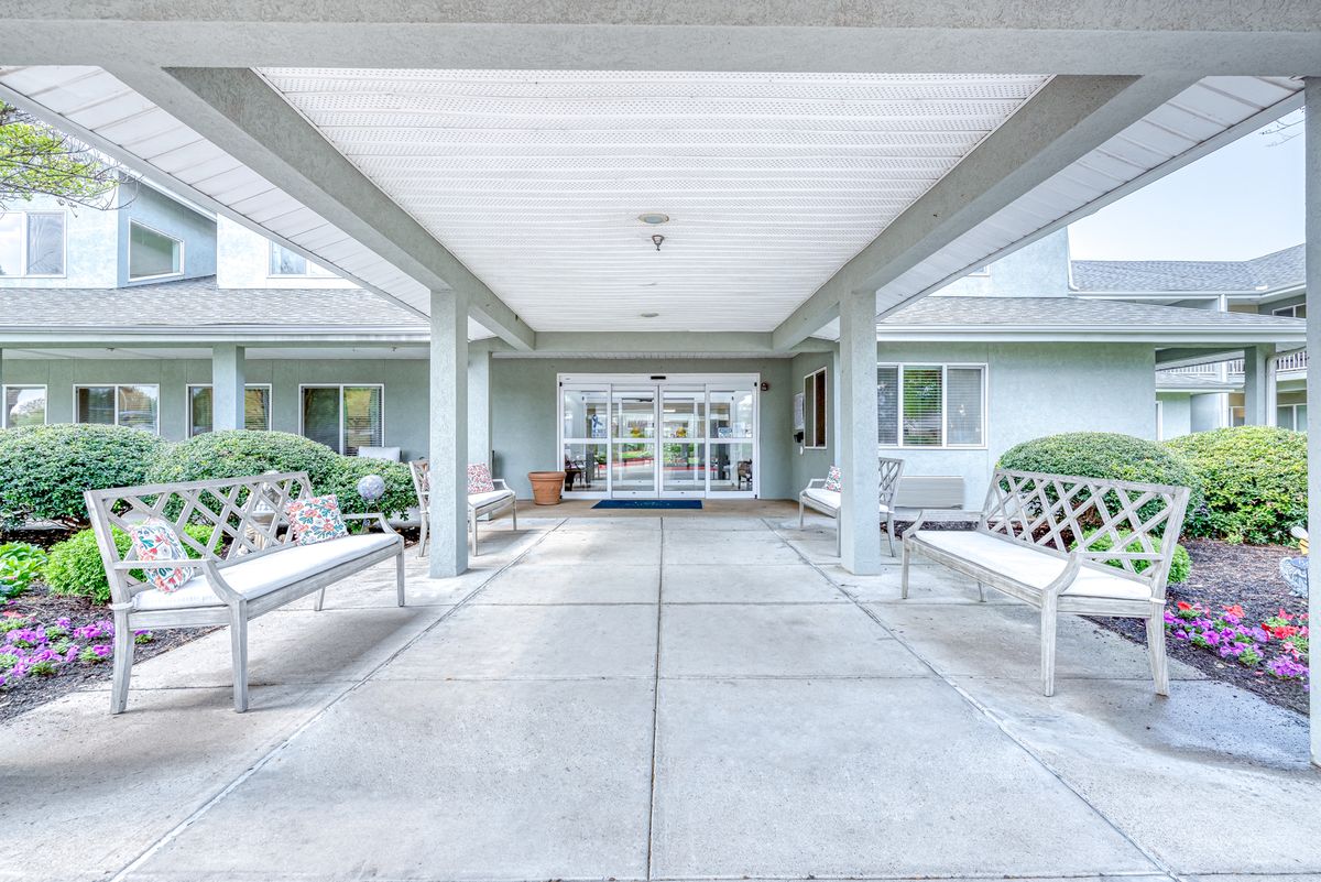 Covered entrance with benches leading to a residential building.