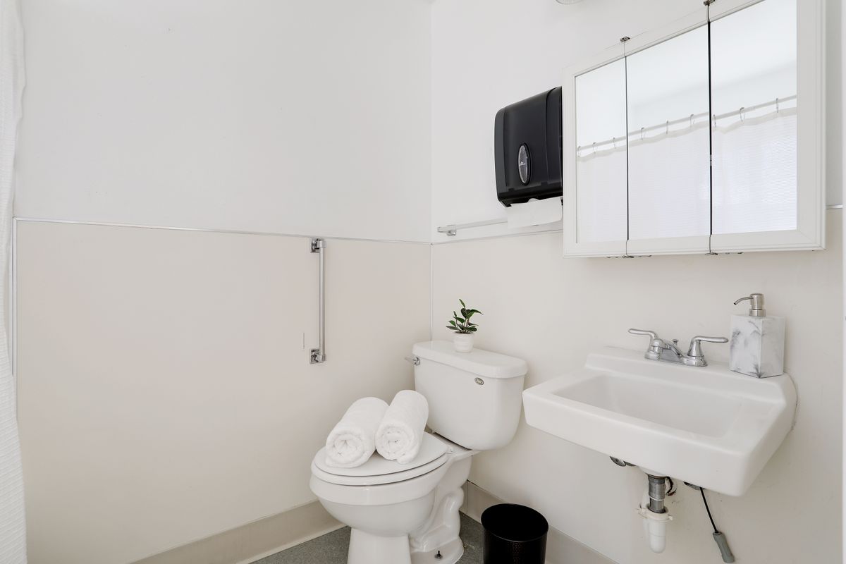 A minimalist bathroom with a toilet, sink, mirror, and neatly folded towels.