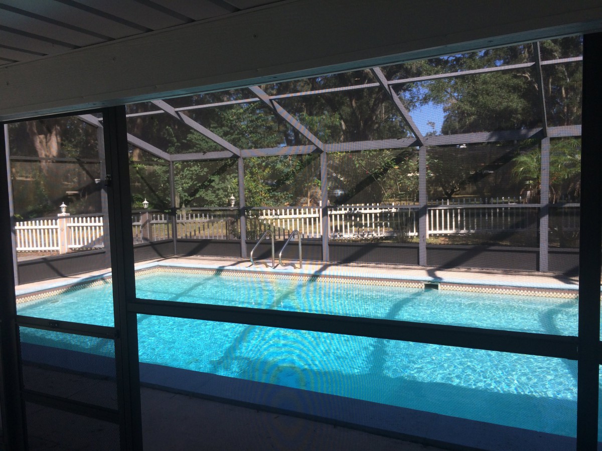 A fenced outdoor swimming pool under a sunny sky.