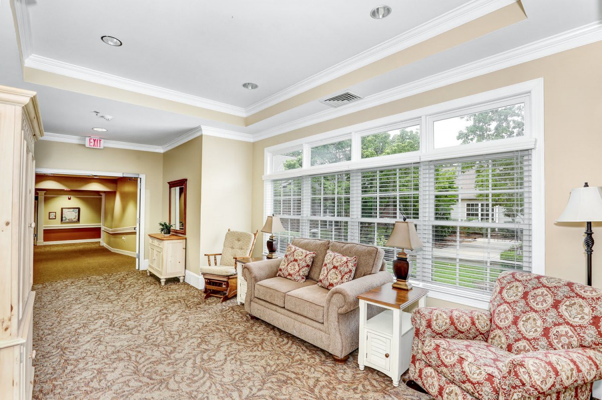 A cozy living room with a large window, comfortable couch, and armchair.