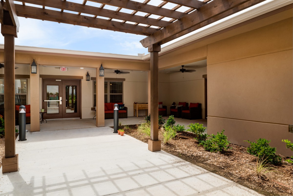 A modern courtyard with a pergola, outdoor seating, and landscaped garden.