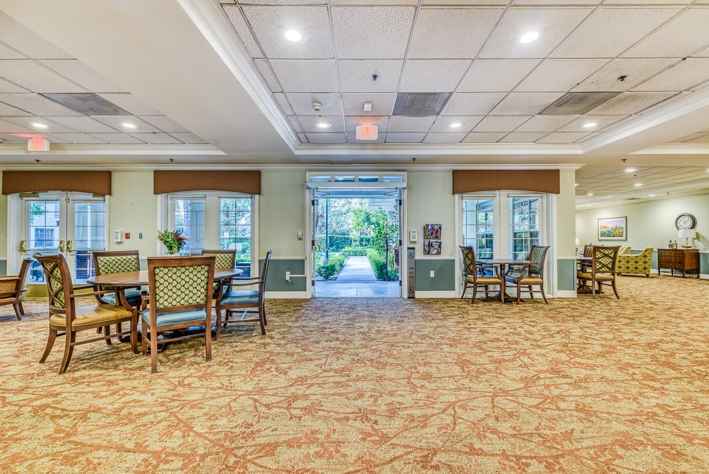 A spacious lobby area with furniture, including tables and chairs, decorated in a bright and welcoming style.