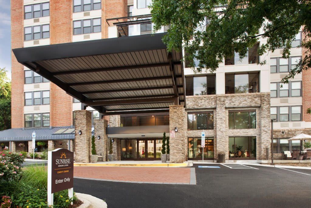 Exterior view of a modern hotel entrance with a canopy and stone facade.