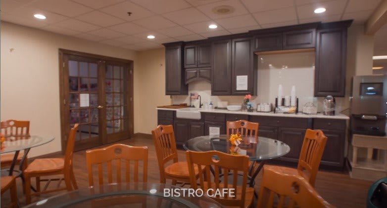 A cozy bistro cafe with wooden furniture and a small kitchen area.