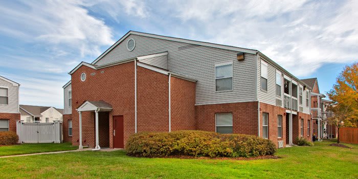 A suburban residential building with brick and siding exterior under a cloudy sky.