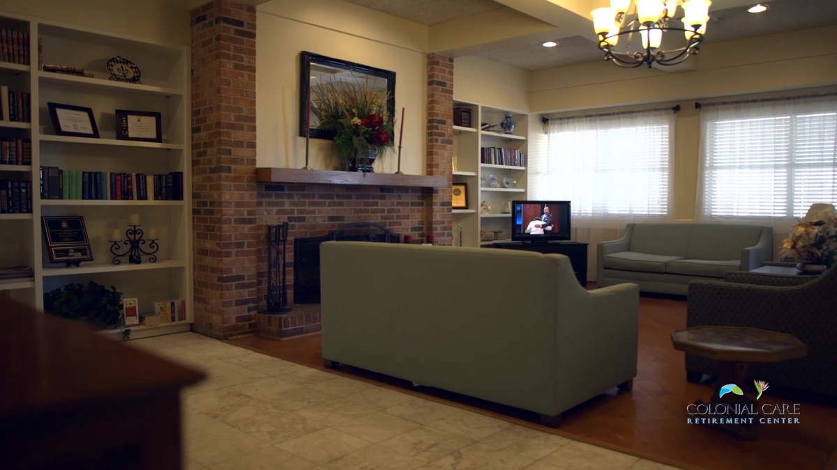 A cozy living room featuring a brick fireplace, a sofa facing a television, and bookshelves for storage.