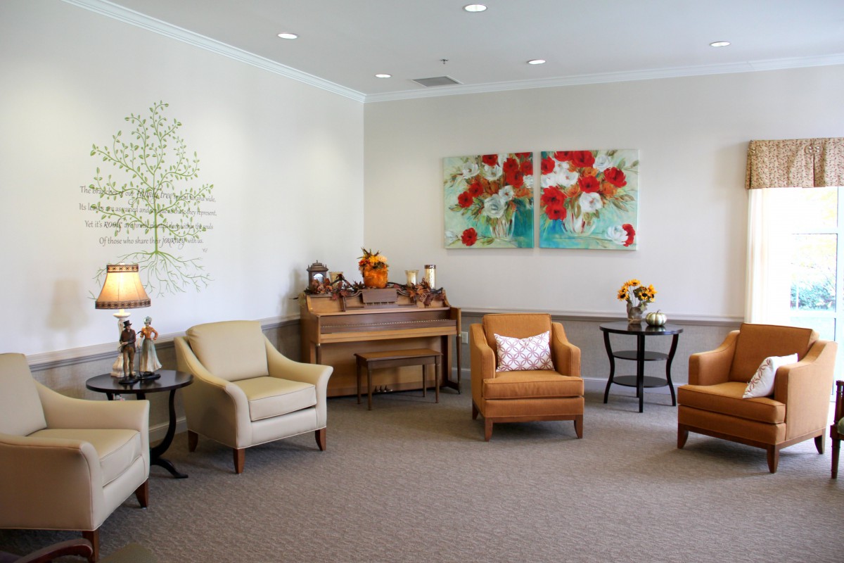 A cozy waiting room featuring comfortable seating, a piano, and colorful artwork on the wall.