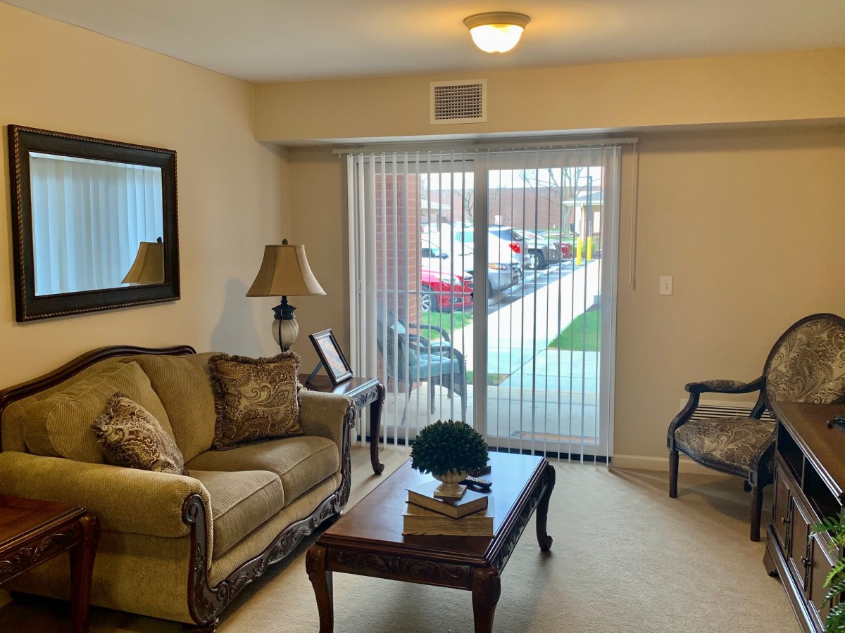 A cozy living room with a sofa, coffee table, and sliding glass door leading outside.