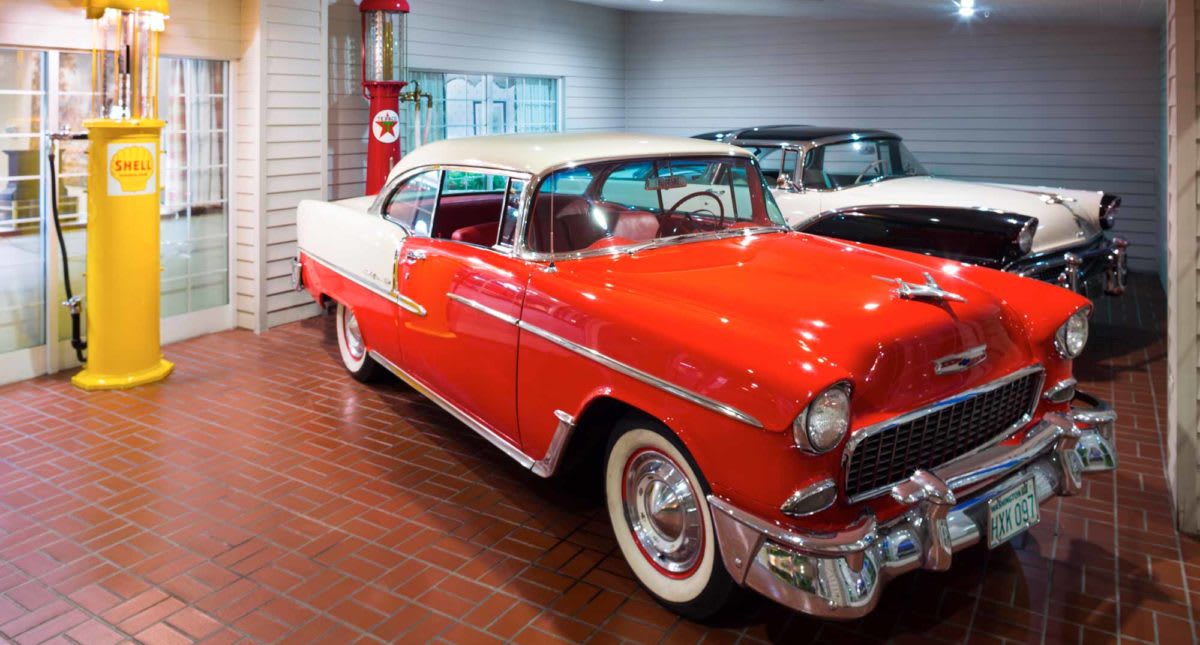 A red and white classic car displayed in a showroom.
