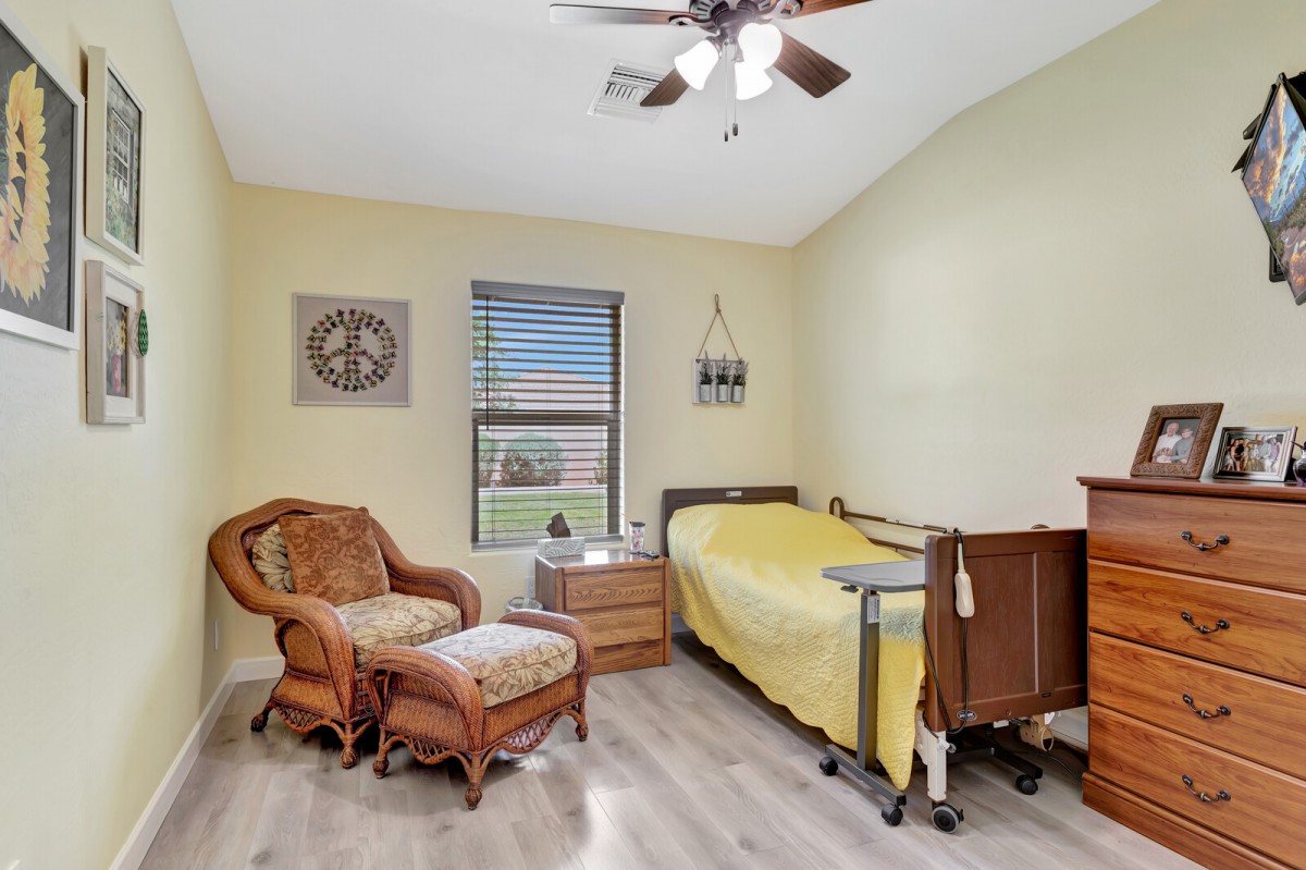 A cozy bedroom with a single bed, armchair, and natural light from the window.