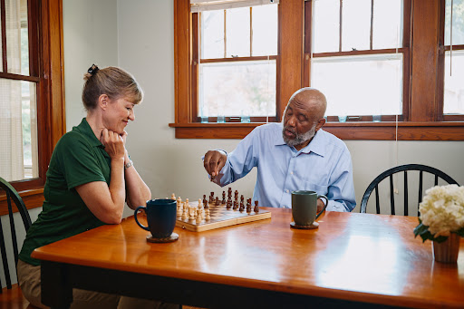 Two individuals engaged in a thoughtful game of chess, surrounded by coffee cups in a cozy indoor environment.