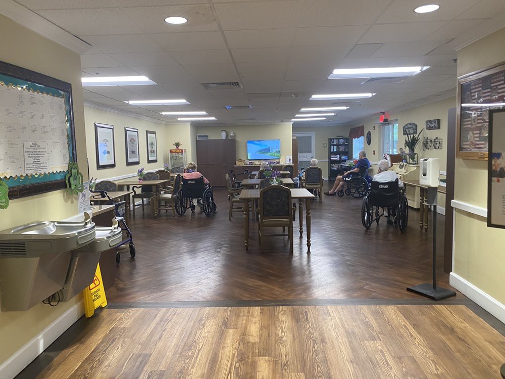Interior view of a nursing home dining area with tables, chairs, and some residents.