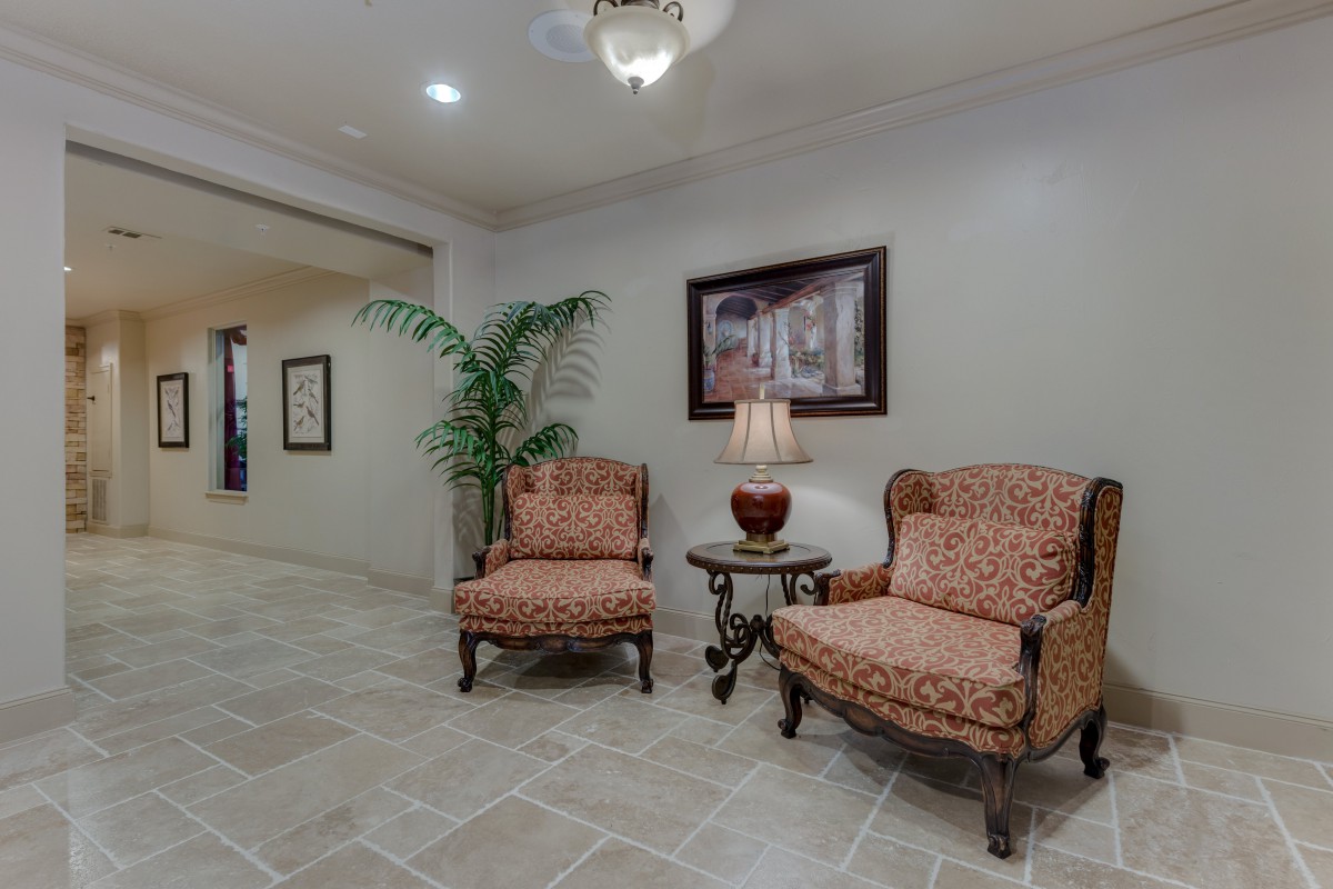 A cozy lobby area with two upholstered chairs and a side table topped with a lamp, complemented by a decorative plant and artwork on the wall.