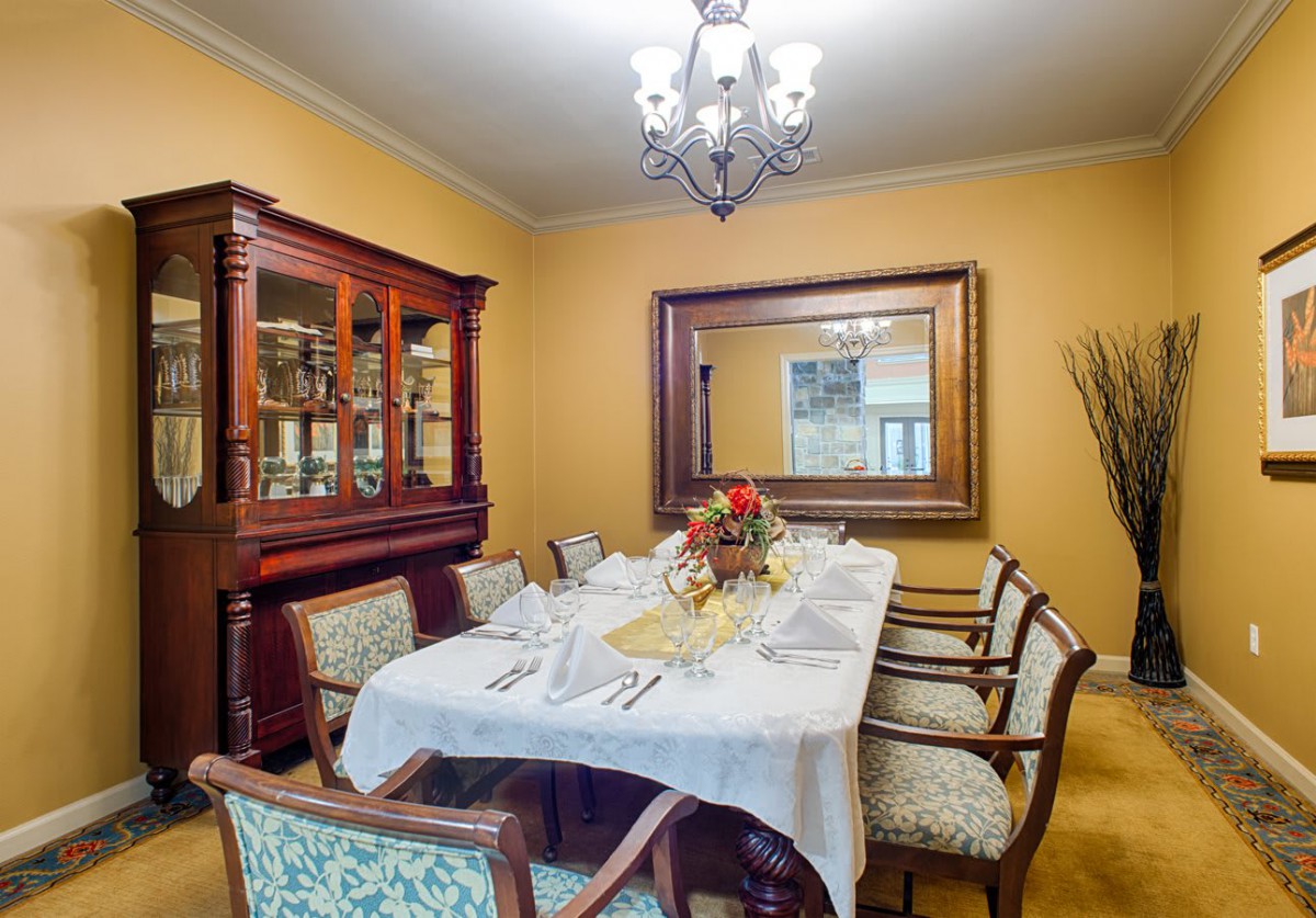 A well-decorated dining room with a table set for a meal, featuring a chandelier, mirror, and classic furniture.